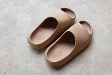 Çimento zeminine izole edilmiş, açık ayak parmağı yastıklı bir çift slayt. Kadın modası. Kadın yaz ayakkabıları, yumuşak terlikler.