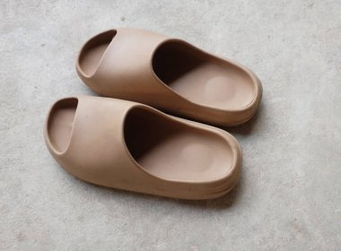 Çimento zeminine izole edilmiş, açık ayak parmağı yastıklı bir çift slayt. Kadın modası. Kadın yaz ayakkabıları, yumuşak terlikler.