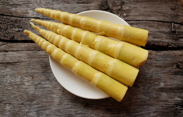 pile of boiled bamboo (Bambusa spp.) shoots inwhite plate isolated on a wooden plate.food processing from plants or vegetables. local thai food ingredients