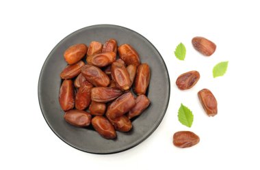 Lezzetli kuru hurma yığınları ya da palmiye ağaçları ya da palmiye anka kuşu dactylifera meyveli siyah seramik plato beyaz arka planda. Atıştırmalık sağlıklı, Arap yemeği, tropikal meyve