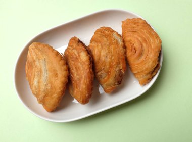 Kızarmış körili börek, körili börek, karipap, epok çağ, sarmal körili puf yeşil pastel bir fon izole etti. Thai körili puf kavramı. Bu pasta Asya 'nın geleneksel atıştırmalıkları.