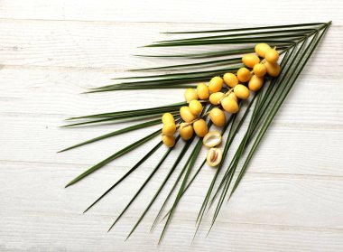 Beyaz arka planda izole edilmiş yeşil yapraklı bir avuç sarı hurma. Tayland meyvesi