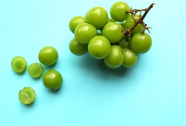 Bir demet taze yeşil parlak muscat (vitis vinifera) üzüm ve yaprak güzel renkli bir kağıda izole edilmiştir. Yeşil üzümler. Japon üzümleri.