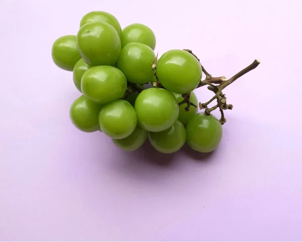 新鮮な甘い緑色の輝きのマスカット ビティスワニ のブドウと葉は 美しい色の紫色の背景に単離されています 緑のブドウ 日本のブドウ — ストック写真