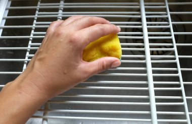 Kadın elinde sarı bir sünger, buzdolabı raflarını temizliyor, buzdolabını mikrofiber bezle temizliyor, buzdolabını deterjanla yıkıyor. Temizlik servisi, ev hanımı., 
