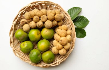 Üst ve düz bir yığın taze tatlı olgun Thai meyvesi portakalı, Tayland 'ın beyaz arka planında izole edilmiş bambu sepetinde yaprağı olan Longkong.