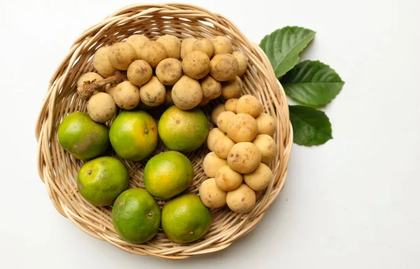 Üst ve düz bir yığın taze tatlı olgun Thai meyvesi portakalı, Tayland 'ın beyaz arka planında izole edilmiş bambu sepetinde yaprağı olan Longkong.