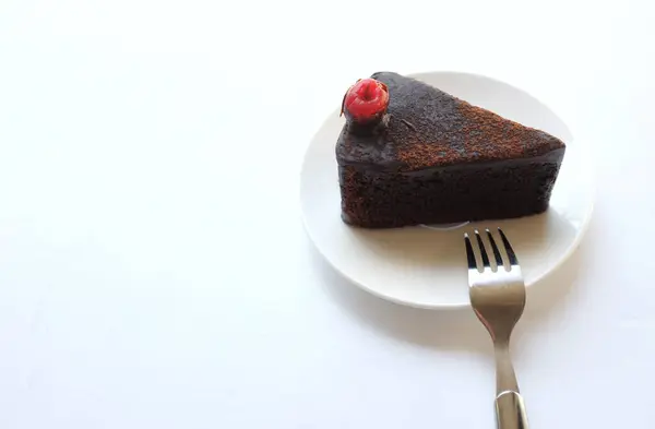 复制空间在白色背景上用红色樱桃隔离装饰的一层黑巧克力蛋糕的一部分 — 图库照片