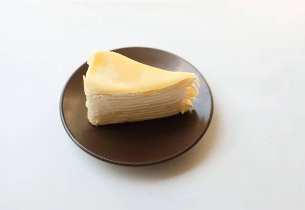 顶部视图和平面放置了一部分分层芝士蛋糕在一个白色的盘子与叉子服务甜点隔离在白色的背景 — 图库照片