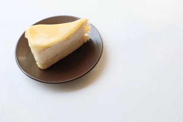 上の景色と平らなレイヤーチーズケーキの一部を白いプレートに置き 白い背景に単離されたデザートのフォークを提供します — ストック写真