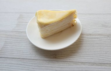 Üst ve düz bir porsiyon peynirli keki beyaz bir tabağa koyup tatlı olarak çatalla servis eder beyaz ahşap bir arka planda izole eder.