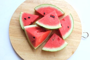 Olgunlaşmış karpuz (Citrullus lanatus) üçgenleri tahta kesme tahtasında beyaz arka planda izole edilir.