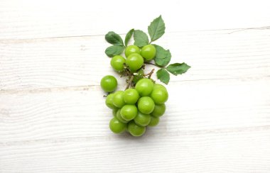 İştah açıcı taze Japon muscat üzümü ve yaprakları beyaz ahşap arka planda izole edilmiş yeşil üzümler. Japon üzümleri.