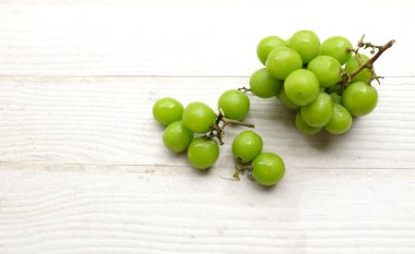 İştah açıcı taze Japon muscat üzümü ve yaprakları beyaz ahşap arka planda izole edilmiş yeşil üzümler. Japon üzümleri.