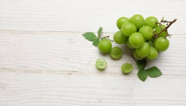 İştah açıcı taze Japon muscat üzümü ve yaprakları beyaz ahşap arka planda izole edilmiş yeşil üzümler. Japon üzümleri.