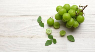 İştah açıcı taze Japon muscat üzümü ve yaprakları beyaz ahşap arka planda izole edilmiş yeşil üzümler. Japon üzümleri.