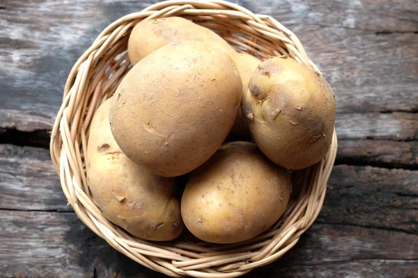 heaps of fresh raw baby potato (Solanum tuberosum) head or Young potato In a wicker basket on a wooden tabl