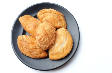 Körili poğaça resmi, yerel olarak Karipap olarak bilinen kıvırcık börek beyaz arka planda izole edilir. Çıtır kabuklu geleneksel çerez. Thai çıtır körili puf kavramı.