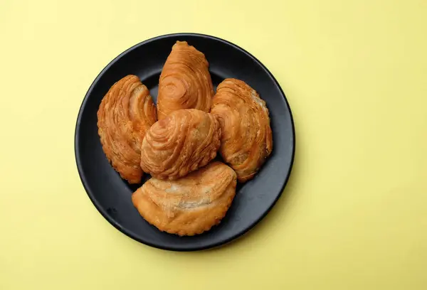 Image of curry puff ,Curry puff pastry, locally known as karipap isolate on a yellow backdrop.Asian traditional snacks that has crispy shell. Thai crispy curry puff concept.