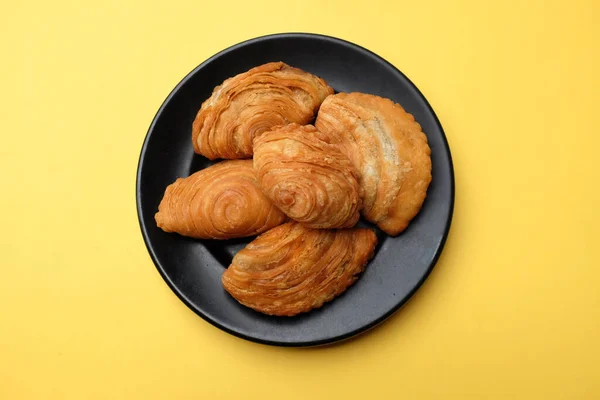 Image of curry puff ,Curry puff pastry, locally known as karipap isolate on a yellow backdrop.Asian traditional snacks that has crispy shell. Thai crispy curry puff concept.