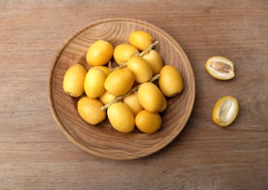 Taze palmiye anka kuşu dactylifera meyvesi ya da ahşap bir arka planda bir tabakta hurma meyvesi. 