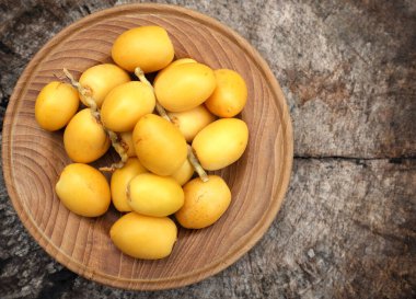 Taze palmiye anka kuşu dactylifera meyvesi ya da ahşap bir arka planda bir tabakta hurma meyvesi. 