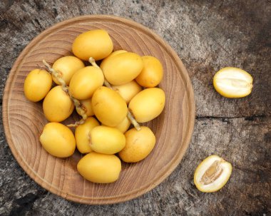 Taze palmiye anka kuşu dactylifera meyvesi ya da ahşap bir arka planda bir tabakta hurma meyvesi. 