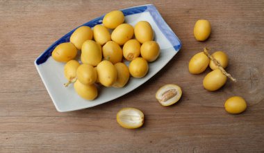 Taze palmiye anka kuşu dactylifera meyvesi ya da ahşap bir arka planda bir tabakta hurma meyvesi. 