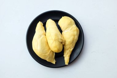 İştah açıcı taze sarı durian parçaları siyah bir plaka beyaz bir zemin üzerinde izole edilir.