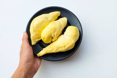 Asyalı bir kadının eli taze, taze, olgun, durian parçalarını siyah bir tabakta tutuyor. Beyaz bir zemin üzerinde izole edilmiş. 