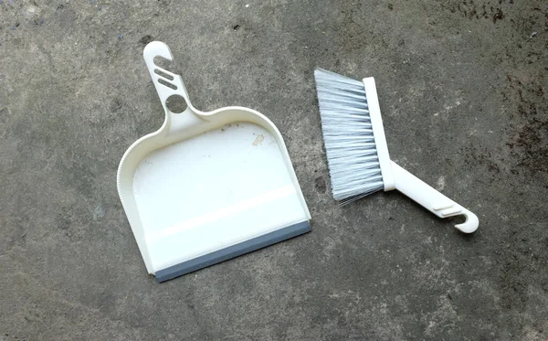 set of plastic hand brooms, dustpan on acement floor  .health care and cleaning home ,cleaning, service, hygiene concept