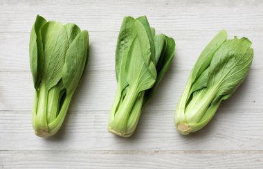 Taze ve lezzetli yeşil yapraklar Bok choy, Çin lahanası, Kanton marulu, Bok Choy (Çin lahanası) küçük choy sum, yeşil pak choi, Çin pazarı (brassica rapa subsp. Beyaz bir ahşap üzerinde