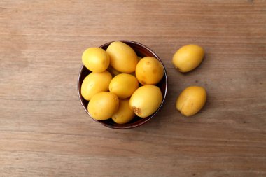 Taze palmiye anka kuşu dactylifera ya da ahşap bir arka planda bir kasede hurma meyvesi.