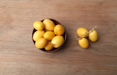 Taze palmiye anka kuşu dactylifera ya da ahşap bir arka planda bir kasede hurma meyvesi.