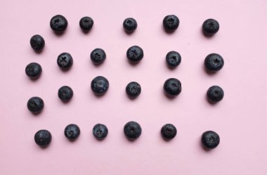 Düz kompozisyonda pembe pastel arka planda taze sulu böğürtlenler vardı. Sağlıklı yeme kavramı. Organik gıda, antioksidan, vitamin, mavi gıda. Yabanmersini desenli. Berrie taze.