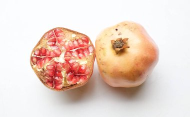 Taze olgun kırmızı bir nar, (punica granatum) beyaz arka planda yarı izole edilmiş yeşil yapraklı. Konsept sağlıklı meyve.