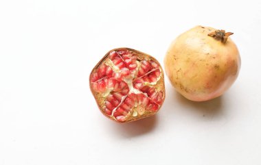 Taze olgun kırmızı bir nar, (punica granatum) beyaz arka planda yarı izole edilmiş yeşil yapraklı. Konsept sağlıklı meyve.