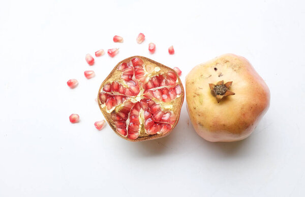 close up a fresh ripe red pomegranate, (punica granatum) with green leaf cut in half isolated on white backdrop.concept healthy fruit