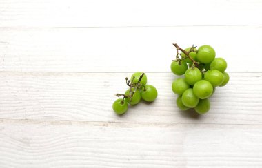 Beyaz ahşap arka planda izole edilmiş güzel bir demet parlak Muscat üzümü.