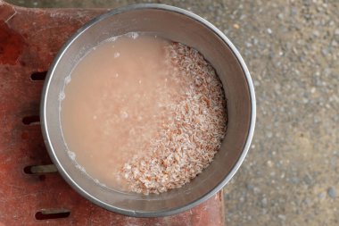 Pişmeden önce organik kırmızı pirinci bir kap suya batırın. Sağlıklı pirinç manzarası ve düz yerde yatar.