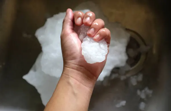 Ice from the freezer in the palm of hand asian woman close up