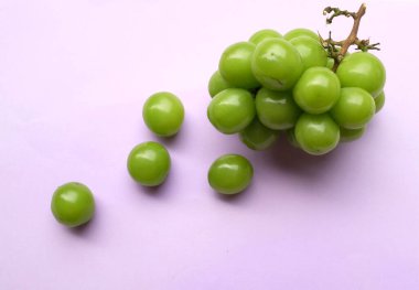 Bir demet taze tatlı yeşil misk kedisi (Vitis vinifera) üzümü mor arka planda izole edilmiş. Yeşil üzümler. Japon üzümleri. Üzüm yeşili. Tadı tatlı ve doğal..