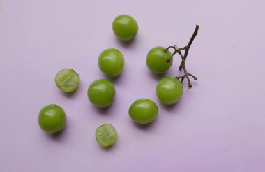 Bir demet taze tatlı yeşil misk kedisi (Vitis vinifera) üzümü mor arka planda izole edilmiş. Yeşil üzümler. Japon üzümleri. Üzüm yeşili. Tadı tatlı ve doğal..