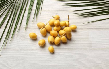 Palmiye anka kuşu dactylifera 'nın üst ve düz grup meyveleri veya yeşil yapraklı hurma meyveleri beyaz zemin üzerinde izole