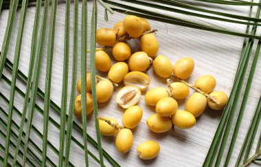 Palmiye anka kuşu dactylifera 'nın üst ve düz grup meyveleri veya yeşil yapraklı hurma meyveleri beyaz zemin üzerinde izole