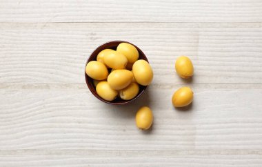 Palmiye ağaçlarının sarı meyvelerinden oluşan bir grup Dactylifera ya da beyaz ahşap masa arka planında izole edilmiş palmiye meyveleri. Sağlıklı yiyecek, geleneksel, lezzetli ve sağlıklı ramazan.