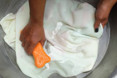 Asyalı ev hanımı, alüminyum leğen içinde köpük deterjanlı bez fırça veriyor. Çamaşır konsepti..