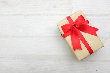 Beyaz hediye kutusunun kuş bakışı görüntüsü. Kırmızı kurdeleli. Tahta masadaki beyaz ve boş bir masa.