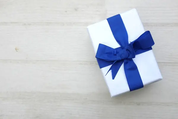 a bird\'s eye view of photo of  gift box  white with blue ribbon bow isolated on a white on the wooden table with empty space