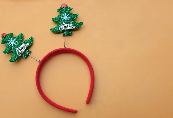 Beautiful headband funny christmas trees isolate on a light orange backdrop.concept of joyful Christmas party,New year is coming soon, festive season decoration with Christmas elements